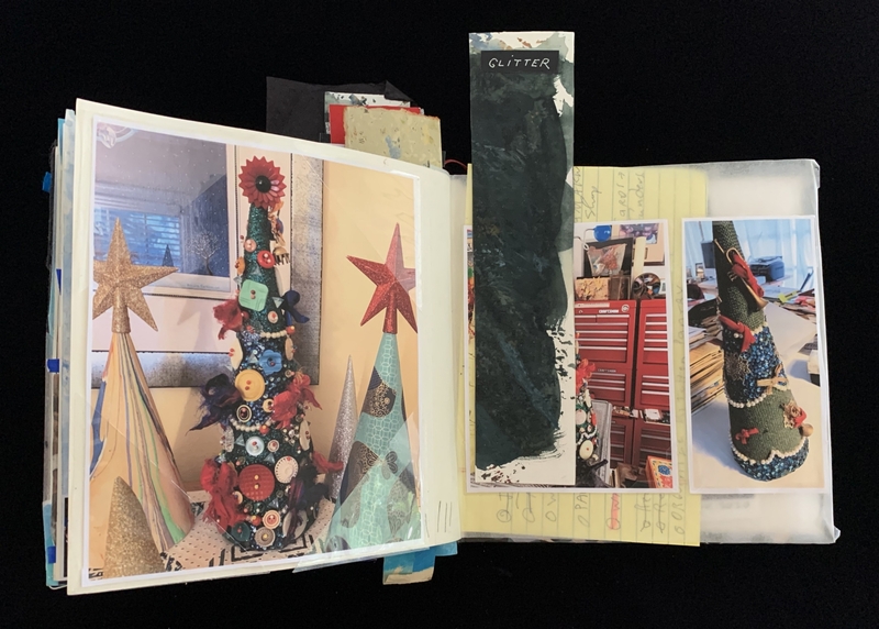 Open scrapbook displaying decorated Christmas tree cones with buttons and star ornaments, and handwritten notes.