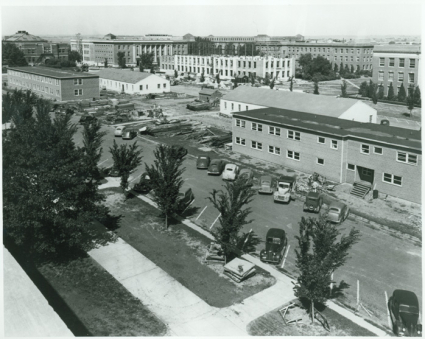Temporary buildings in foreground, with Burnett Hall under construction. Partially demolished old Nebraska Hall is in the upper left corner.