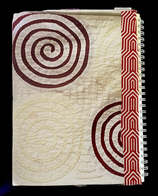A spiral notebook cover featuring a central red spiral, smaller concentric circles, and a red geometric pattern on the spine.