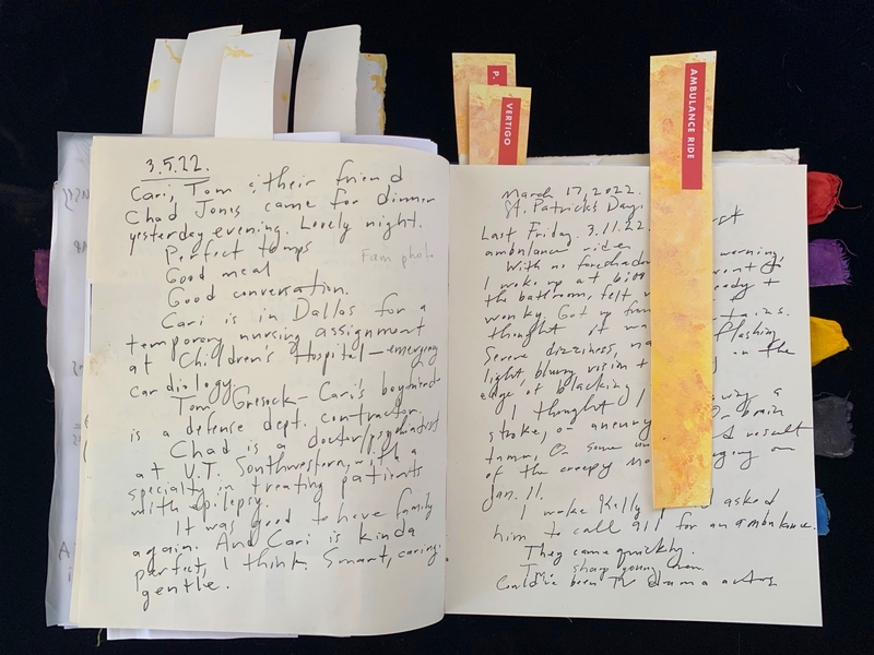 An open journal with handwritten text and labeled bookmarks.