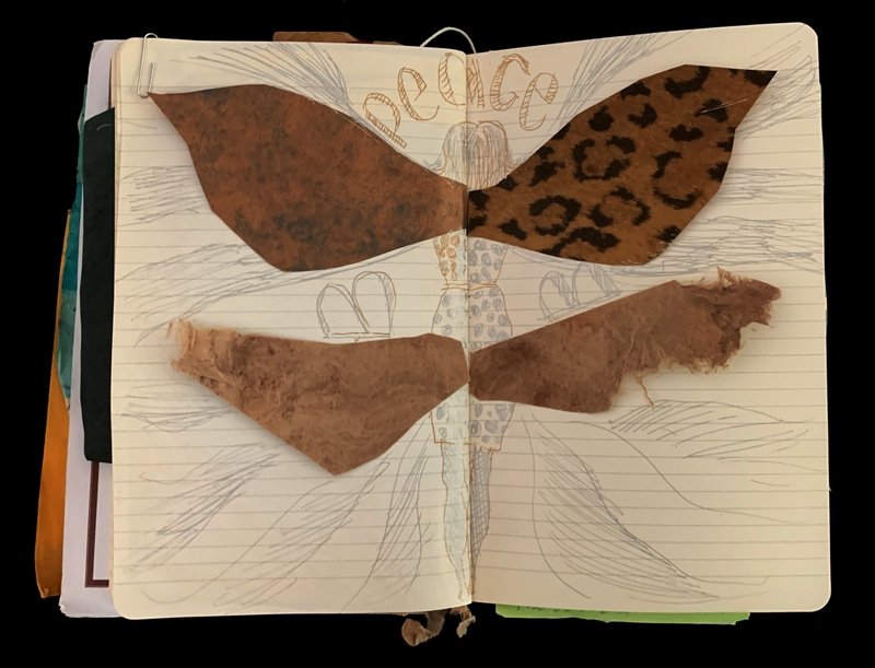 An open notebook with a collage of textile pieces forming a butterfly and the word "Peace" sketched above.