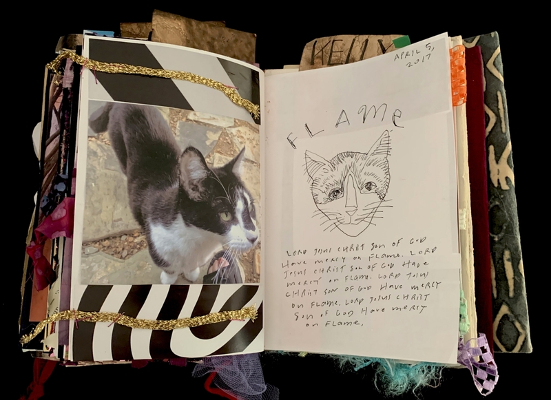 A scrapbook page featuring a photograph of a black and white cat, a drawing of the same cat, and handwritten text.