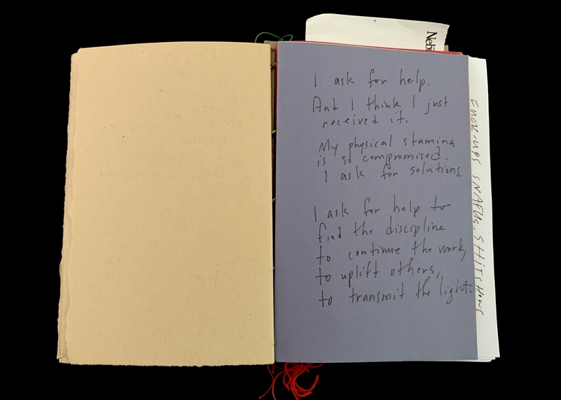 Open book with blank beige page on the left and handwritten text on blue page on the right.