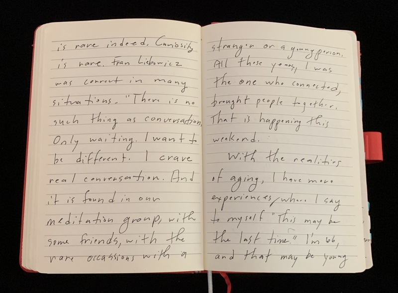 Open notebook with two pages of handwritten cursive text about conversations and aging.
