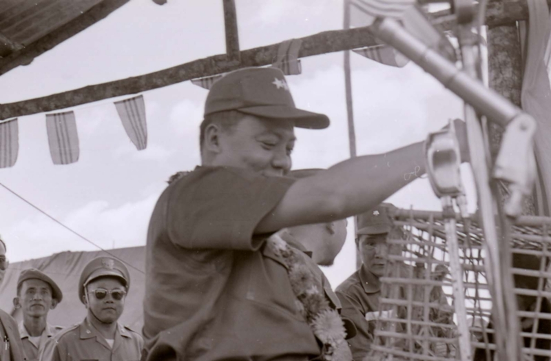 Nguyá»…n KhÃ¡nh appears to be looking at some kind of animal placed inside a cage. He appears to be grabbing the cage to hold.