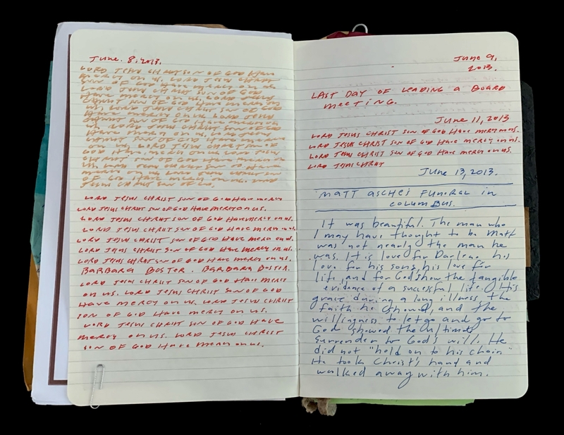 Open notebook with handwritten notes in orange and blue ink.