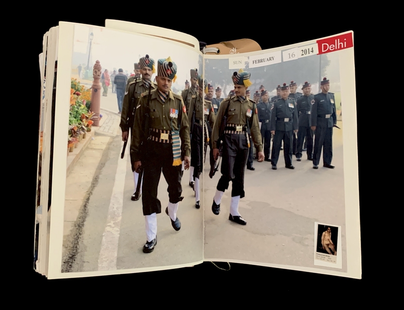 Photograph of uniformed soldiers walking in an outdoor parade, shown in an open book.