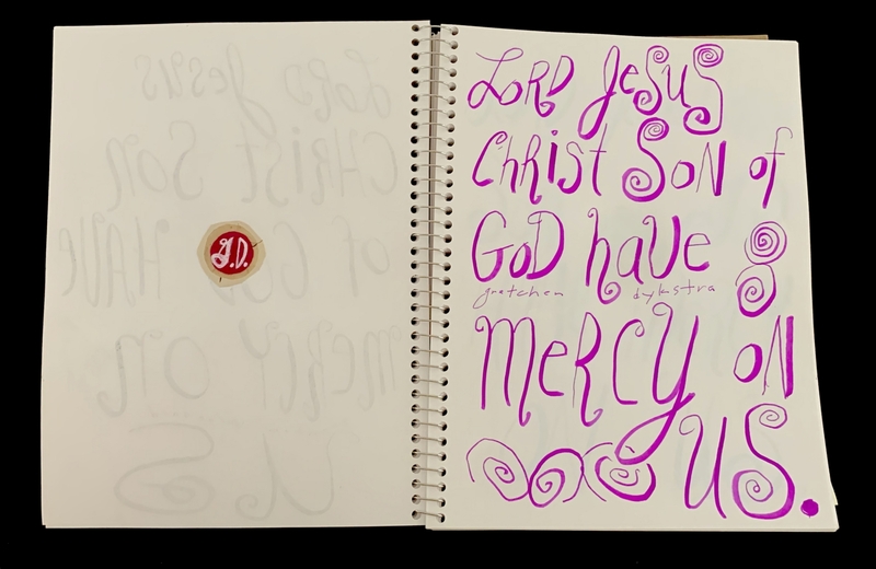 A page from a spiral-bound notebook featuring a handwritten prayer and faintly visible