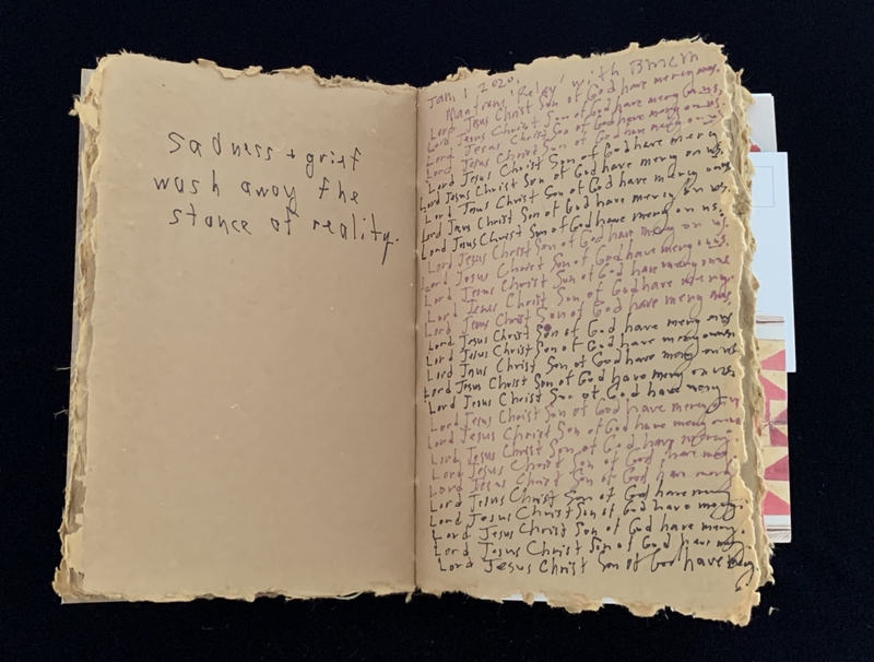 An open book with aged, rough-edged pages; the left side has a handwritten message, and the right side is densely filled with repetitive text.