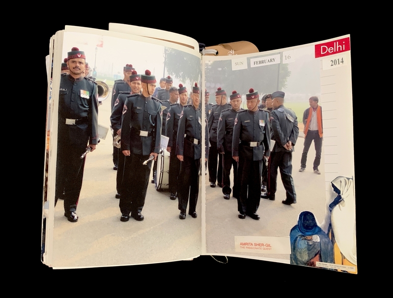 An open book showing a photo of uniformed men and a calendar page dated February 16, 2014.