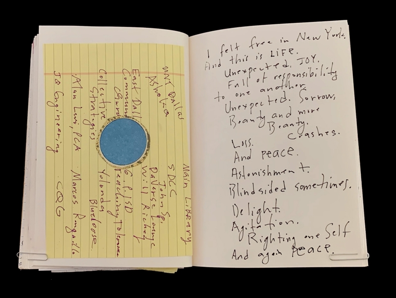 Open notebook with handwritten text on yellow lined paper and white paper.