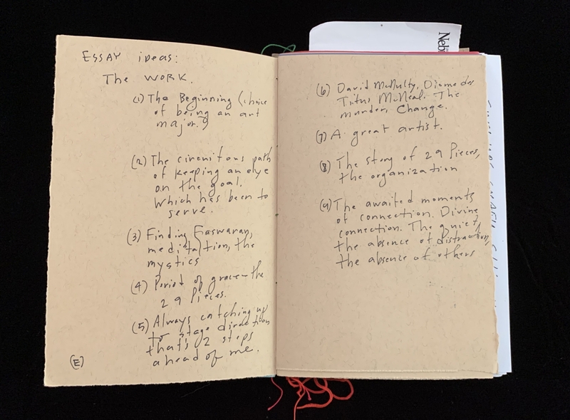 Open notebook with handwritten essay ideas listed on two pages.