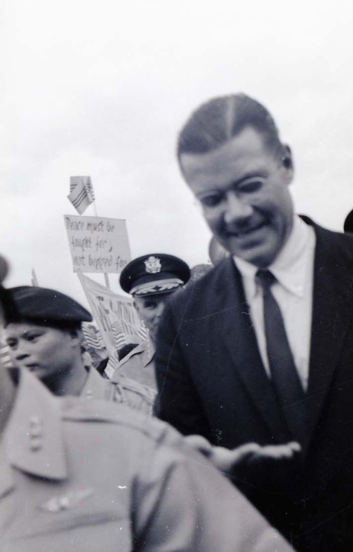 Robert McNamara walks through a crowd of people.
