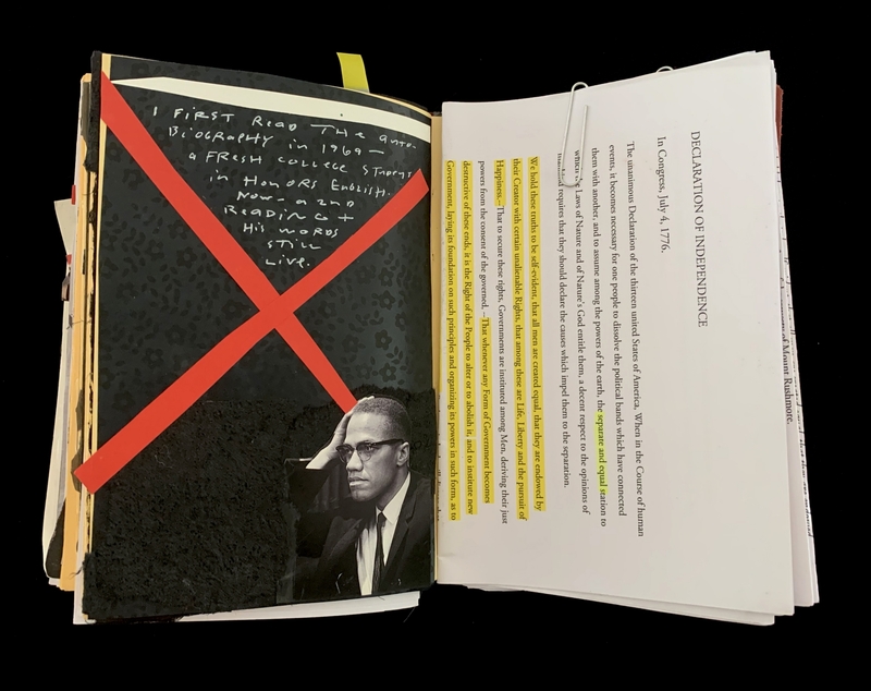 A book page with a red "X" over a photograph and a transcription of the Declaration of Independence.