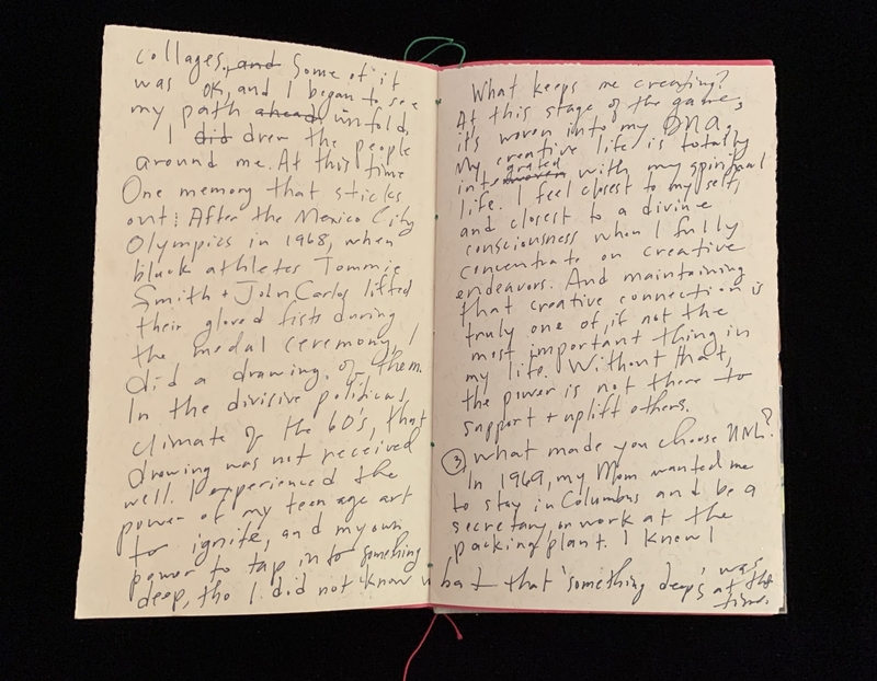 Open notebook with handwritten cursive text on off-white pages, bound with red stitching.