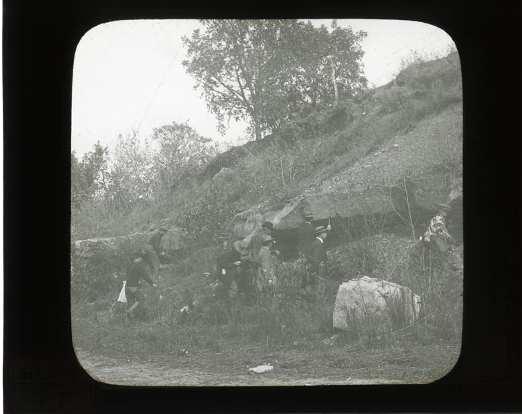 Original caption: The flint ledge at old quarry opp. So. Bend, Nebr. 1911 Group of men standing at base of flint ledge. Cass County. (121111-00247)