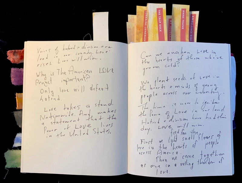 An open journal with handwritten text on love and unity. Colorful fabric tabs are on the left, and labeled bookmarks protrude from the top.