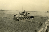 "Operation 'Junction City,' Vietnam - An M48A3 (Patton) tank of the 11th Armored Cavalry Regiment rampages through rice paddies in search of Viet Cong troops being routed by the U.S. Army's multi-divisional sweep of War Zone 'C'. Code named 'Junction City' the current sweep is the largest operation of the conflict in Vietnam." An American tank crossing an open field.