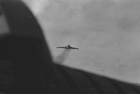 A plane in flight. Landing gear is still visible. Photo taken from another plane.