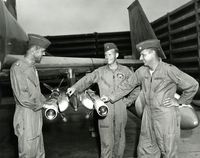 "This is How We Did It - Air Force Major Robert G. Dilger, 34, of Tampa Fla., an F-4C Phantom aircraft commander (right) and his pilot, First Lieutenant Mack Thies, 26, of Houston (center), explain to Lieutenant Colonel Hoyt S. Vandenberg Jr., 38, Washington, D.C., how they forced down a MIG-17 during an aerial dogfight over North Vietnam yesterday (May 1). Colonel Vandenberg is the commander is the commander of the 390th Tactical Fighter Squadron at Da Nang air base. The MIG kill was the second for the 390th in a week and the 36th confirmed Air Force Kill." Three American pilots gathered around the missiles of a fighter jet.