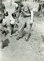 An American soldier named Hibbs takes the hand of a young Vietnamese child.