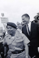 Robert McNamara walks behind Nguyá»…n KhÃ¡nh in a crowd. Henry Cabot Lodge, Jr., walks behind them.