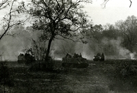 "Operation 'Junction City,' Vietnam - Armored Cavalry Assault Vehicles (ACAV's) of the 11th Armored Calvary Regiment prowl for Viet Cong troops in War Zone C during the fourth day of Operation 'Junction City,' Feb 26. The modified Armored Personnel Carrier are flanked by M60 machineguns and fire a .50 caliber machinegun forward. The fast moving, fast firing ACAV's carry a combat ready squad of Army troops, and have yet to be bested in a fight against enemy forces in Vietnam." Three tanks with soldiers riding on them drive through a foggy or dusty meadow. There is a forest in the background.