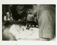 "'Doctor' Les Lagada, Navy Seabee Hospital Corpsman first class of Putol, Republic of the Philippines, examines a Vietnamese infant during village sick call. Lagda makes his medical rounds five times a week at which time he treats 50 to 100 Vietnamese daily. Because of his efforts, Lagda is 'Bac Si' - 'Number One' - in the eyes of the villagers. Lagda is part of the 13-man U.S. Navy Seabee Team 0406 which is located in Bao Trai conducting civic action projects for the South Vietnamese. It is sponsored by the U.S. Agency for International Development (USAID) along with seven other such teams from U.S. Naval Construction Battalions in Vietnam." A Seabee doctor examines a Vietnamese infant. Seabees news release 25-67 (64).