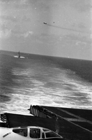 "7th Fleet" A view of the open ocean. An aircraft carrier and an ascending plane can be seen in the background. Photo taken from a second aircraft carrier.