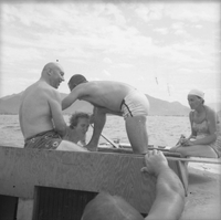 A group American men and women sitting on boat in swimsuits.