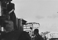 "7th Fleet" Two American men working on a large piece of machinery. A Naval plane can be seen in the background.