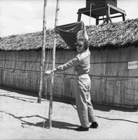 An American woman hangs a pair of shorts like a flag on a pole outside.