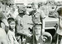 An American soldier named Hibbs is waving to villagers after handing out supplies, possibly soap.