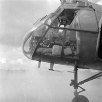 "Dogs", picture of the front of a helicopter with two pilots in the cockpit. From the camera angle, it is hard to tell whether the helicopter is in flight.