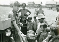 An American soldier named Hibbs is handing out supplies to villagers. He is holding what may be soap.