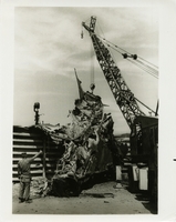 Original title: "Seabees Quick on Job."  "U.S. Naval Mobile Construction Battalion SEVEN instantly rushed equipment to DaNang Air Base in South Vietnam recently to help clear the field of aircraft destroyed in an early morning Viet Cong attack. Among those responding to the Air Force request for assistance are Navy Seabees George J. Furtado (operating crane) and Robert L. Bowman (signaling directions). Seabee Battalion SEVEN is based at DaNang East to provide support to combat units. This year, Seabees mark the 25th anniversary of their organization, which served outstandingly in World War II and Korea--and is doing so again in Vietnam." Clearing debris off of air field with a crane. Seabees news release RVN 242 (58).