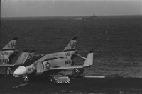 "7th Fleet" Navy airplanes sitting on an aircraft carrier in open water. A second aircraft carrier can be seen in the background.