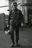 "Carrier Air Wing Nine Aviators from the USS Enterprise hit the KEP airfield 37 miles northeast of Hanoi, this morning. Capt. James L. Shipman, of Aurora, MO, joined Skyhawk pilots on the mission. 'There were four plans on the apron and no MIG's in the air ' He said, 'that's the way to get them... on the ground.'" An American Navy pilot in uniform walks toward the camera.