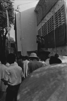 "Students wrecking min. of info." Two young men stand above a crowd. Behind them is a building.