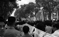 "Unidentified", Photo of a protest. A large crowd of Vietnamese people walk in a tree lined street with banners.