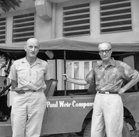 Two American men pose for a picture in front of a jeep.