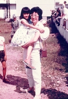 Beverly Deepe Keever is holding a young Vietnamese girl and posing for the camera. There are American soldiers in the background.