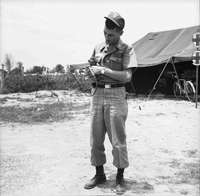 An American soldier holds a small monkey with a leash.