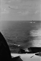 "7th Fleet" A view of the open ocean. An aircraft carrier and an ascending plane can be seen in the background. Photo taken from a second aircraft carrier.