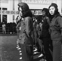 Original caption: "Mne. Nhu + Paramilit. Graduation - 27 Feb 63" A young Vietnamese woman looks at camera as the other women in front of her stand in formation.
