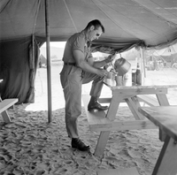 "QN + Train ", picture of a soldier getting tea from a tea pot, placed on a table, in atent