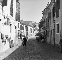 "Macau" A street with people walking and children playing.