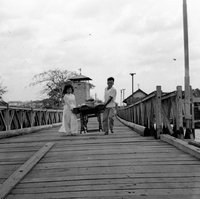 A Vietnamese man and woman carry a sewing machine across a bridge.