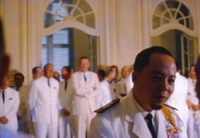 Nguyá»…n KhÃ¡nh dressed in full uniform in a formal French-style room with mirrors. He is surrounded by Vietnamese men in suits.