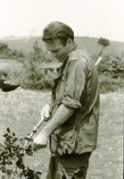 An American soldier cutting off a sapling's branches with a knife.